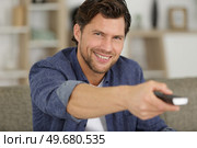smiling man holding remote control. Стоковое фото, агентство Ingram Publishing / Фотобанк Лори