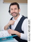 man wearing headset and leafing through folder. Стоковое фото, агентство Ingram Publishing / Фотобанк Лори