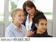 hairdressing apprentice learning to iron clients hair. Стоковое фото, агентство Ingram Publishing / Фотобанк Лори