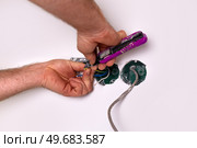 Home renovation project shows hands working on electrical wiring in a wall cavity at a residential location. Стоковое фото, фотограф Виктория Тельминова / Фотобанк Лори
