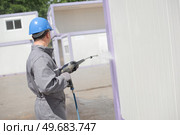 Man power washing portable cabin. Стоковое фото, агентство Ingram Publishing / Фотобанк Лори