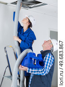 electricians fitting ac hoses in buildings ceiling. Стоковое фото, агентство Ingram Publishing / Фотобанк Лори