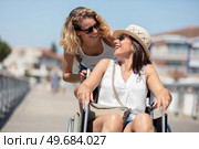 woman with friend in wheelchair crosswalk in city. Стоковое фото, агентство Ingram Publishing / Фотобанк Лори