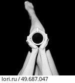 Top view of crop unrecognizable barefooted female sitting in black studio with cup of hot coffee. Crop anonymous woman with coffee cup in black studio. Стоковое фото, агентство Ingram Publishing / Фотобанк Лори
