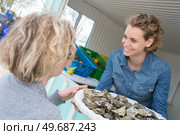 positive female shop assistant selling fresh fish and chilled seafood. Стоковое фото, агентство Ingram Publishing / Фотобанк Лори