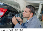 a mechanic fixing rear light. Стоковое фото, агентство Ingram Publishing / Фотобанк Лори