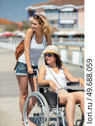 lady on summer holiday pushing disabled friend in a wheelchair. Стоковое фото, агентство Ingram Publishing / Фотобанк Лори