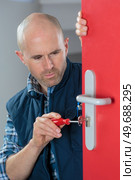 Man fixing lock on internal door. Стоковое фото, агентство Ingram Publishing / Фотобанк Лори