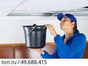 female worker holding bucket under leaking ceiling. Стоковое фото, агентство Ingram Publishing / Фотобанк Лори