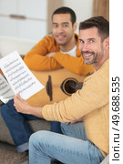 man holding sheet music for man learning the guitar. Стоковое фото, агентство Ingram Publishing / Фотобанк Лори