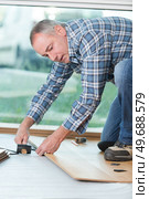 carpenter lining parquet boards to each other fitting a plank. Стоковое фото, агентство Ingram Publishing / Фотобанк Лори