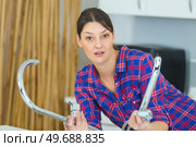 female plumber fixing tap with adjustable wrench. Стоковое фото, агентство Ingram Publishing / Фотобанк Лори