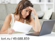 worried woman looks through papers sitting on sofa at home. Стоковое фото, агентство Ingram Publishing / Фотобанк Лори