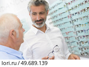 experienced male optician offering frames to elderly client. Стоковое фото, агентство Ingram Publishing / Фотобанк Лори