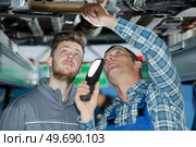 male mechanicsunder lifted car at garage. Стоковое фото, агентство Ingram Publishing / Фотобанк Лори