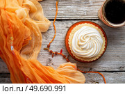 cup of coffee with delicious cream cake with orange scarf  around white old style wooden background. close up. lifestyle concept. Стоковое фото, агентство Ingram Publishing / Фотобанк Лори