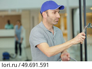 man cleaning window with rag indoors. Стоковое фото, агентство Ingram Publishing / Фотобанк Лори