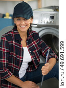 woman fixes a washing machine. Стоковое фото, агентство Ingram Publishing / Фотобанк Лори