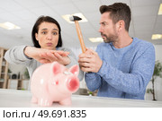 woman stops man from breaking a piggy bank. Стоковое фото, агентство Ingram Publishing / Фотобанк Лори