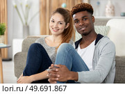 young mixed race couple sat on floor by settee. Стоковое фото, агентство Ingram Publishing / Фотобанк Лори