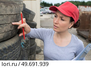 woman checking tread on car tyre with gauge. Стоковое фото, агентство Ingram Publishing / Фотобанк Лори
