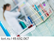 test tubes in foreground female scientist blurred in background. Стоковое фото, агентство Ingram Publishing / Фотобанк Лори