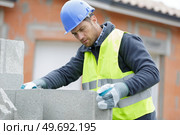 builder man holding concrete blocks for house building. Стоковое фото, агентство Ingram Publishing / Фотобанк Лори