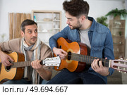 mid adult man teaches guitar to a male student. Стоковое фото, агентство Ingram Publishing / Фотобанк Лори