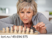 senile old woman playing a game of chess alone. Стоковое фото, агентство Ingram Publishing / Фотобанк Лори