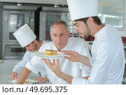 young confectioner presenting cake to chef. Стоковое фото, агентство Ingram Publishing / Фотобанк Лори