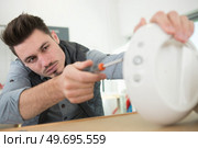 young repairman fixing and repairing appliance. Стоковое фото, агентство Ingram Publishing / Фотобанк Лори