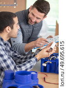 apprentice in workshop assembles ventilation system with his mentor. Стоковое фото, агентство Ingram Publishing / Фотобанк Лори