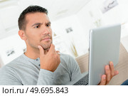portrait of thinking man using laptop computer at home. Стоковое фото, агентство Ingram Publishing / Фотобанк Лори
