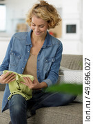 young woman folding clothes on the sofa. Стоковое фото, агентство Ingram Publishing / Фотобанк Лори
