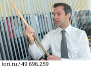 mature seller holding pool cue in his store. Стоковое фото, агентство Ingram Publishing / Фотобанк Лори
