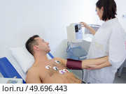 experienced cardiologist attaching sensors to patients chest. Стоковое фото, агентство Ingram Publishing / Фотобанк Лори