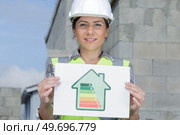 female builder holding sign showing energy symbols for a home. Стоковое фото, агентство Ingram Publishing / Фотобанк Лори