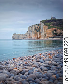 Sightseeing view to Etretat coastline with the famous Notre-Dame de la Garde chapel on the Amont cliff. Pebble beach washed by Atlantic ocean waters, Normandy, France. Стоковое фото, агентство Ingram Publishing / Фотобанк Лори