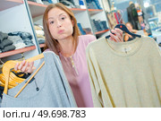 Lady holding two jumpers, cheeks puffed out. Стоковое фото, агентство Ingram Publishing / Фотобанк Лори