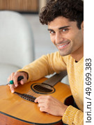 young man changing guitar strings at home. Стоковое фото, агентство Ingram Publishing / Фотобанк Лори