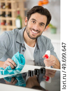 a man spraying detergent to clean the kitchen worktop. Стоковое фото, агентство Ingram Publishing / Фотобанк Лори