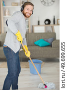 man moping the floor and listening to music on earphones. Стоковое фото, агентство Ingram Publishing / Фотобанк Лори
