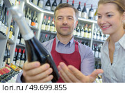 salesman assisting female customer in choosing wine. Стоковое фото, агентство Ingram Publishing / Фотобанк Лори