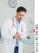 confident male doctor is bandaging upper limb of young woman. Стоковое фото, агентство Ingram Publishing / Фотобанк Лори