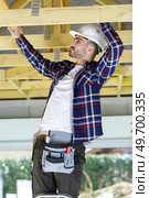 builder reaching up to roof timber. Стоковое фото, агентство Ingram Publishing / Фотобанк Лори