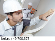 Worker applying masking tape to wall. Стоковое фото, агентство Ingram Publishing / Фотобанк Лори