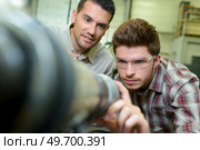 trainee adjusting equipment under his supervisors guidance. Стоковое фото, агентство Ingram Publishing / Фотобанк Лори
