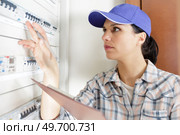 female engineer switches on circuit breakers in electrical box. Стоковое фото, агентство Ingram Publishing / Фотобанк Лори