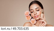 Portrait beautiful young woman with clean fresh skin. Model with foundation makeup bottle. Beautiful young woman with a rose flower. Стоковое фото, агентство Ingram Publishing / Фотобанк Лори