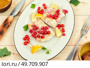 Cod fillet without skin fried with red currants on wooden table. Cod fish. Codfish loin baked with berries. Стоковое фото, агентство Ingram Publishing / Фотобанк Лори